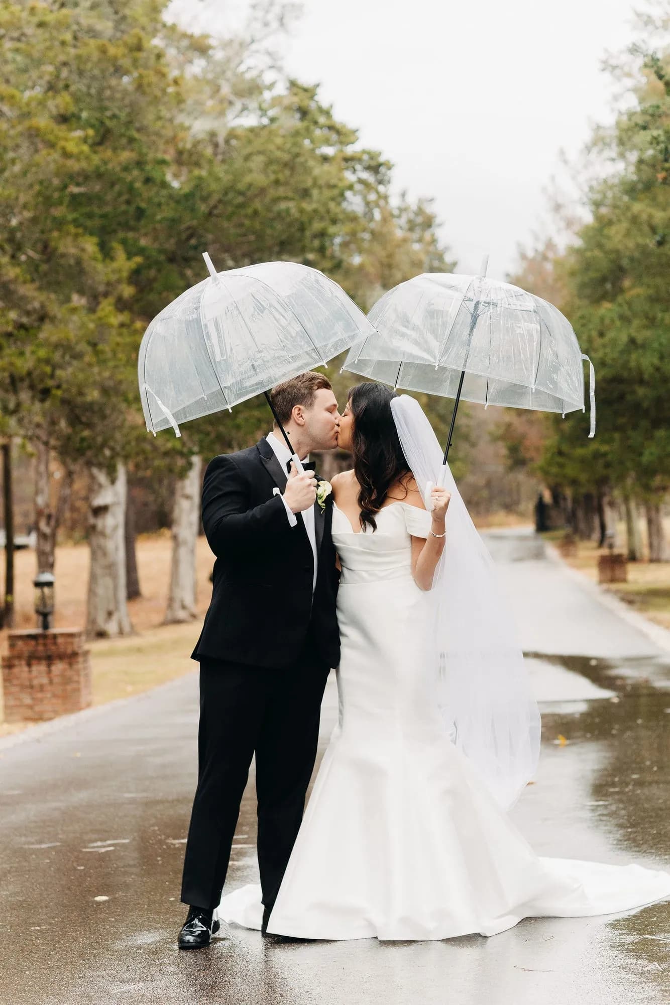 Cindy and Nick kissing beneath an umbrella in soft rain